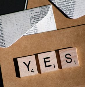 Envelope with Scrabble piece spelling the word "yes"